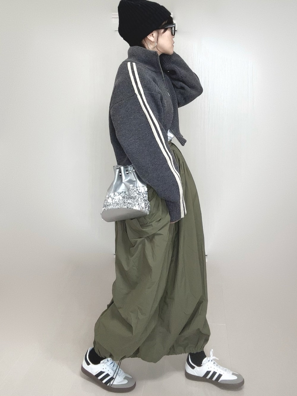 グレー系のニット/セーター、シルバー系のショルダーバッグ、グリーン系のスカートを着用したレディースの冬コーディネートの4枚目の写真