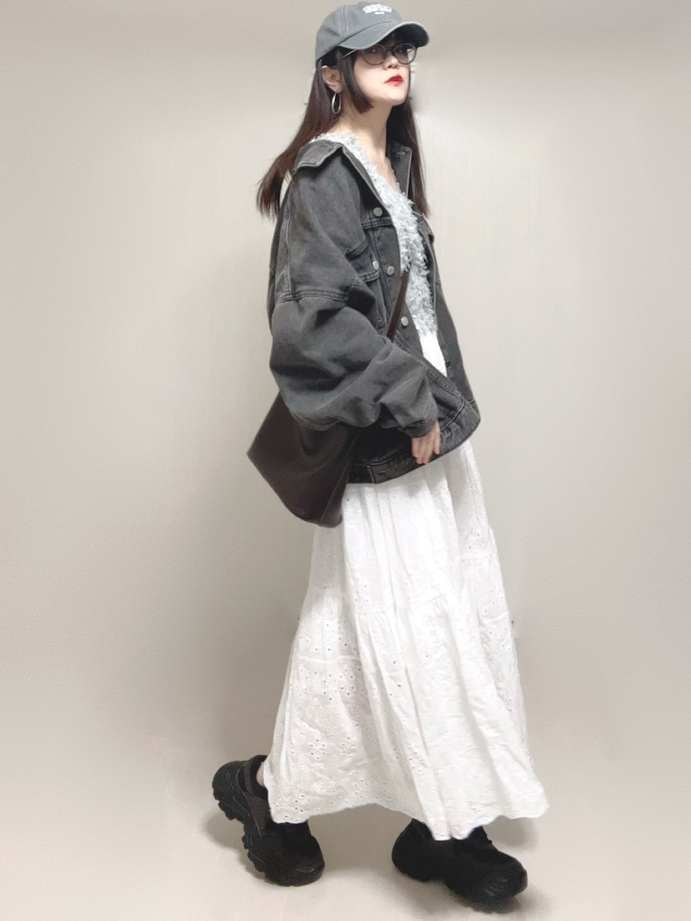 グレー系のベスト、ブラック系のデニムジャケット、ホワイト系のスカートを着用したレディースの春コーディネートの3枚目の写真