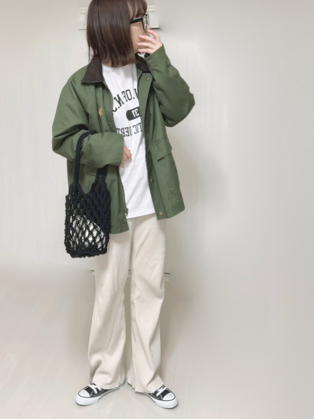 グリーン系のカバーオール、ホワイト系のTシャツ/カットソー、ブラック系のハンドバッグを着用したレディースの春コーディネートの3枚目の写真