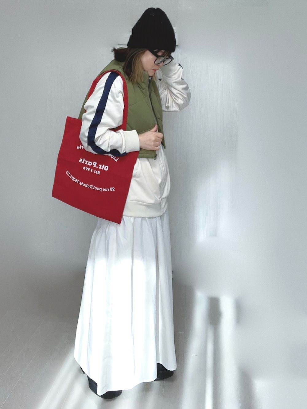 ベージュ系のジャージ、ホワイト系のスカート、ブラック系のブーツを着用したレディースの冬コーディネートの2枚目の写真