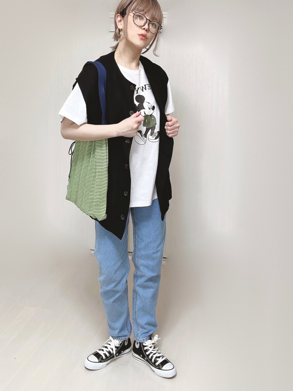 ブルー系のデニムパンツ、ブラック系のベスト、ホワイト系のTシャツ/カットソーを着用したレディースの春コーディネートの2枚目の写真