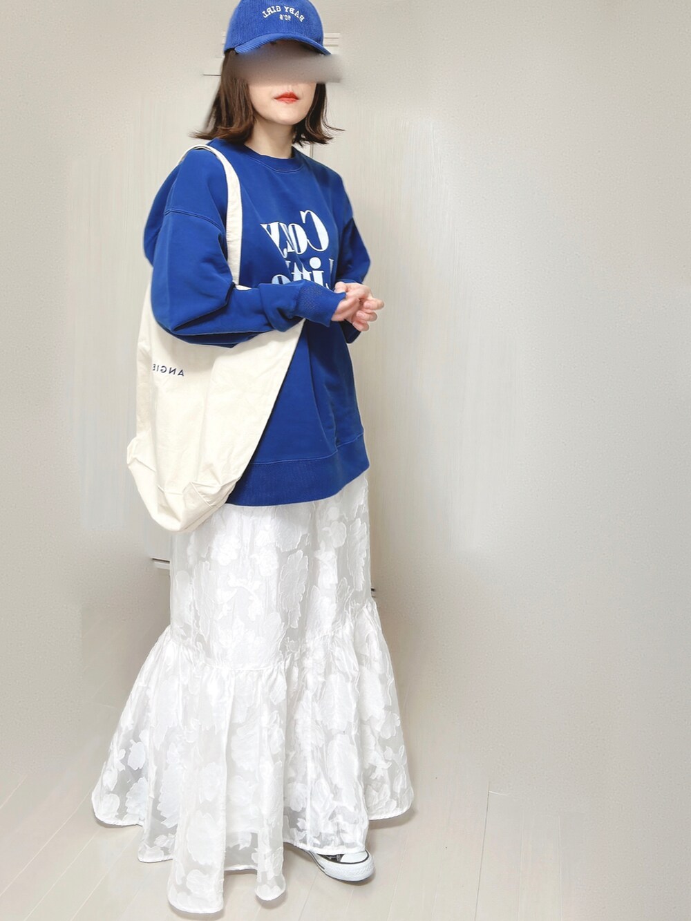 ブルー系のスウェット、ホワイト系のトートバッグ、ホワイト系のスカートを着用したレディースの春コーディネートの4枚目の写真