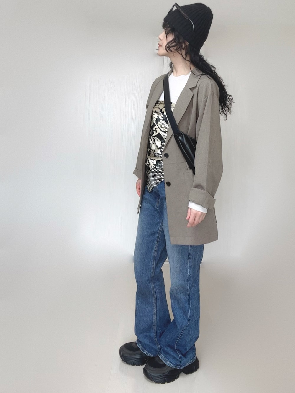 ベージュ系のテーラードジャケット、ブルー系のデニムパンツ、ブラック系のスニーカーを着用したレディースの春コーディネートの3枚目の写真