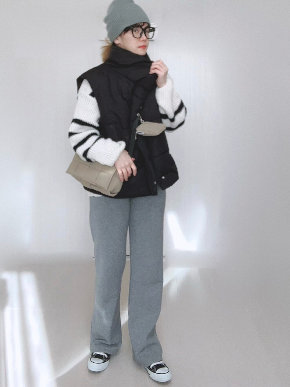 ブラック系のダウンベスト、ホワイト系のニット/セーター、グレー系のその他パンツを着用したレディースの冬コーディネートの5枚目の写真