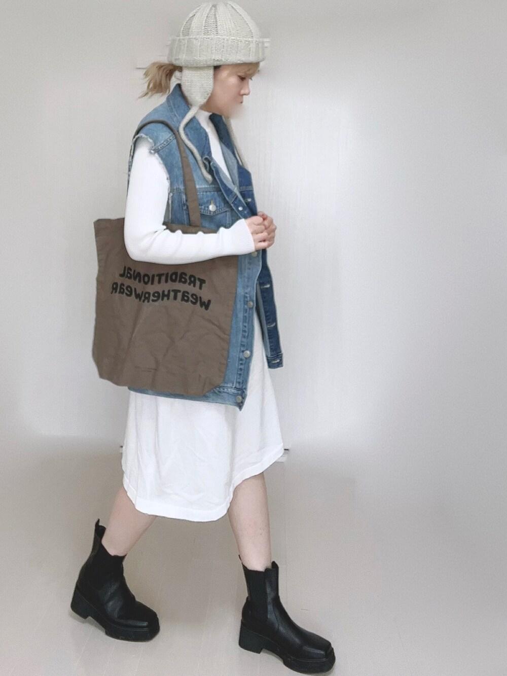 ホワイト系のワンピース、ブルー系のベスト、ブラウン系のトートバッグを着用したレディースの冬コーディネートの3枚目の写真