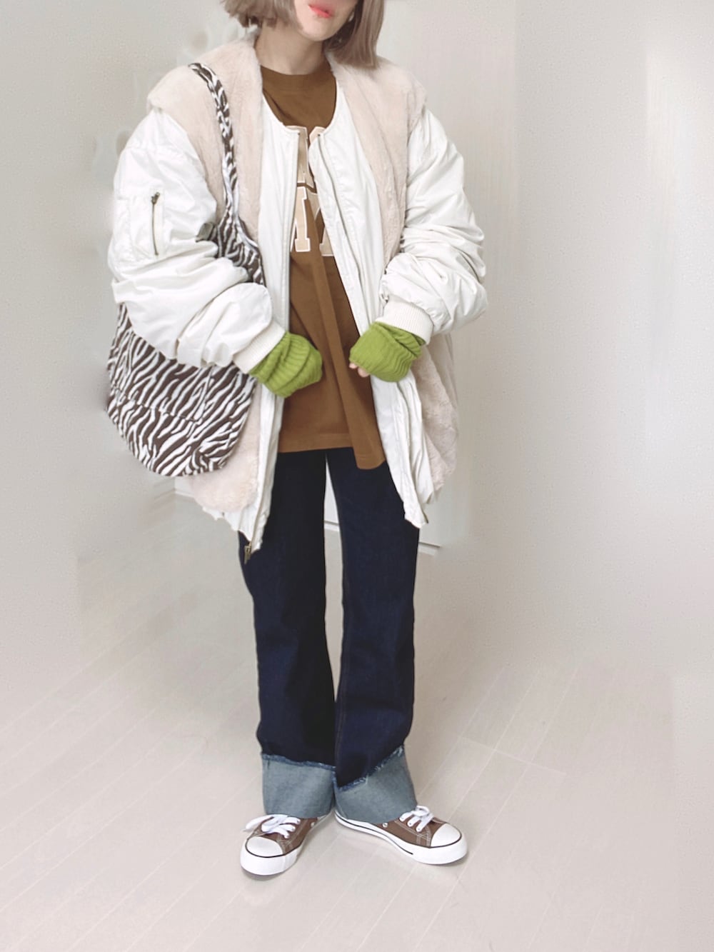 ホワイト系のブルゾン、ブラウン系のTシャツ/カットソー、ブルー系のデニムパンツを着用したレディースの秋コーディネートの4枚目の写真
