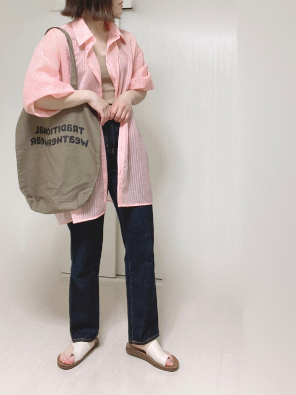 ピンク系のシャツ/ブラウス、ブラウン系のトートバッグ、ブルー系のデニムパンツを着用したレディースの夏コーディネートの2枚目の写真