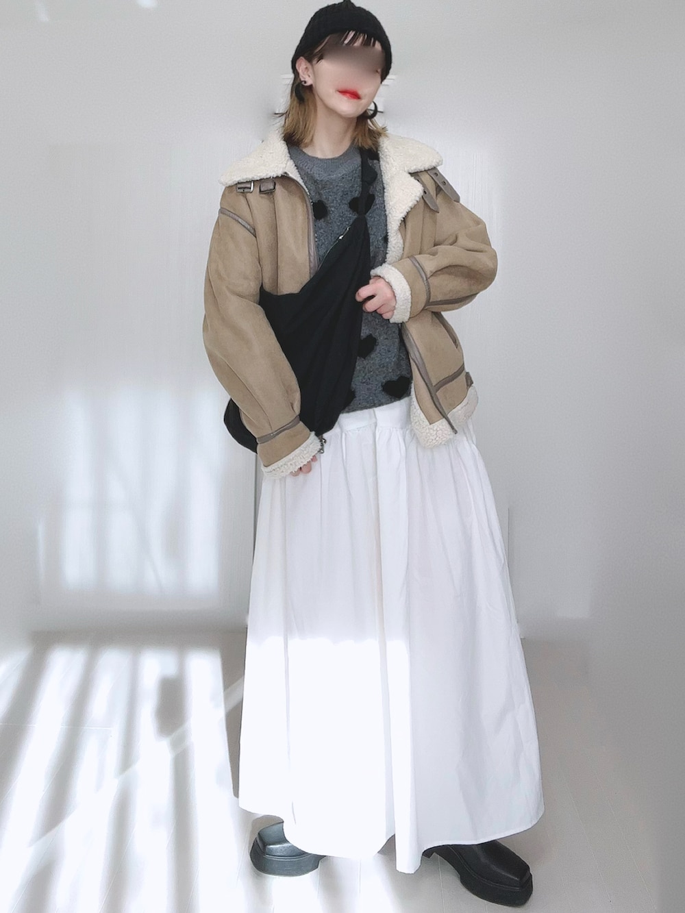 ベージュ系のムートンコート、ホワイト系のスカート、ブラック系のブーツを着用したレディースの冬コーディネートの5枚目の写真