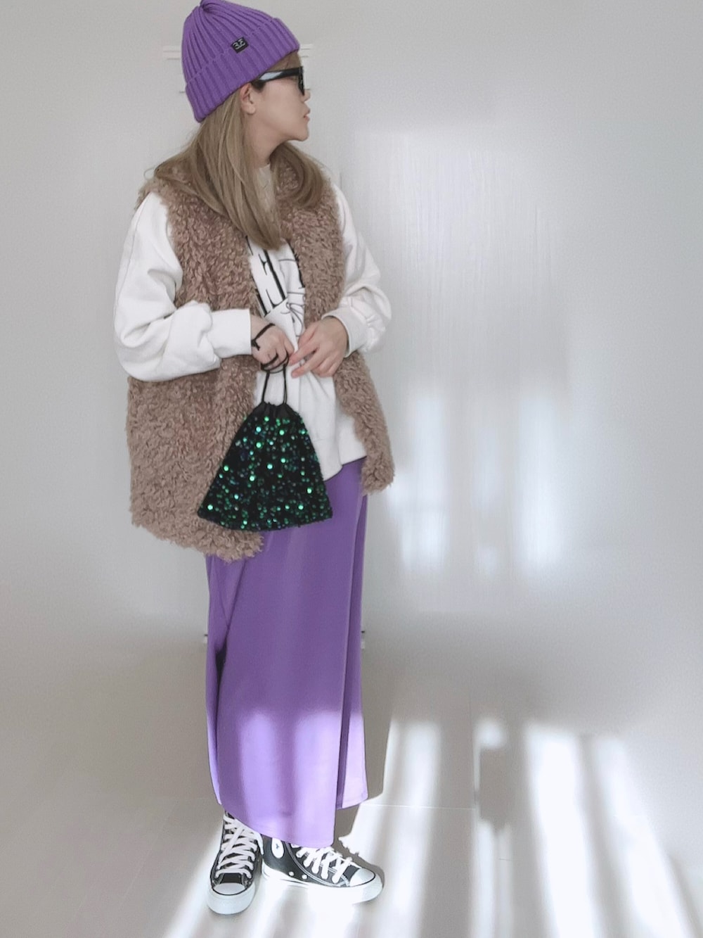 ベージュ系のベスト、パープル系のスカート、ブラック系のスニーカーを着用したレディースの冬コーディネートの2枚目の写真