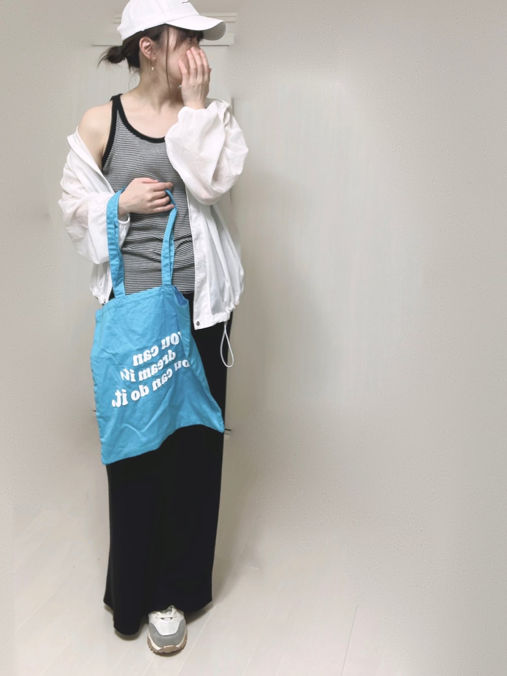ブラック系のスカート、ブラック系のタンクトップ、ブルー系のトートバッグを着用したレディースの春コーディネートの4枚目の写真