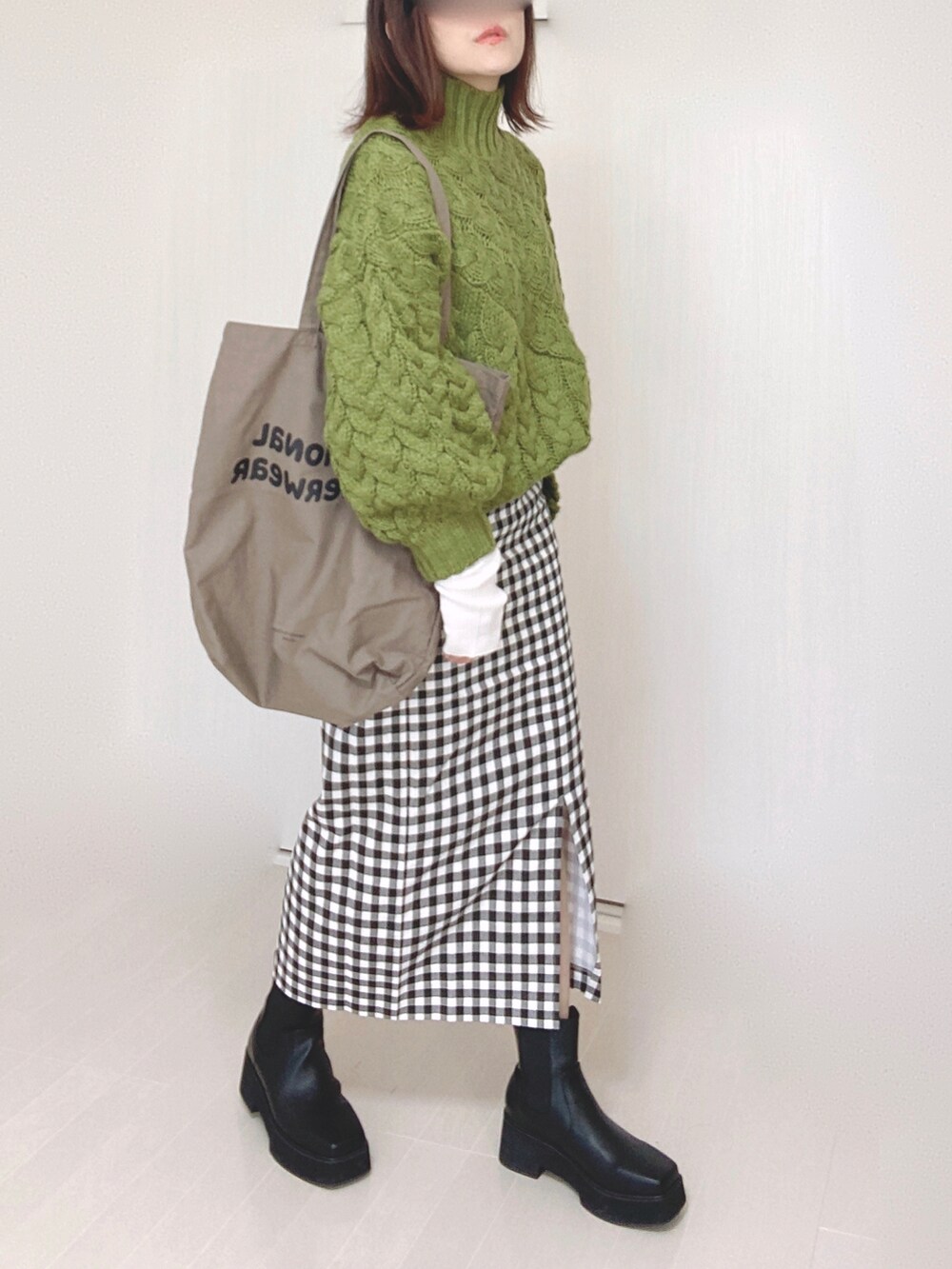 ブラック系のブーツ、グリーン系のニット/セーター、ブラウン系のトートバッグを着用したレディースの冬コーディネートの3枚目の写真
