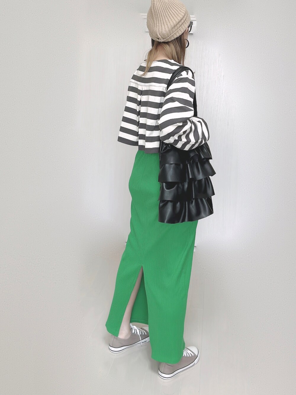 グリーン系のスカート、ベージュ系のニットキャップ/ビーニー、ブラック系のメガネを着用したレディースの秋コーディネートの2枚目の写真