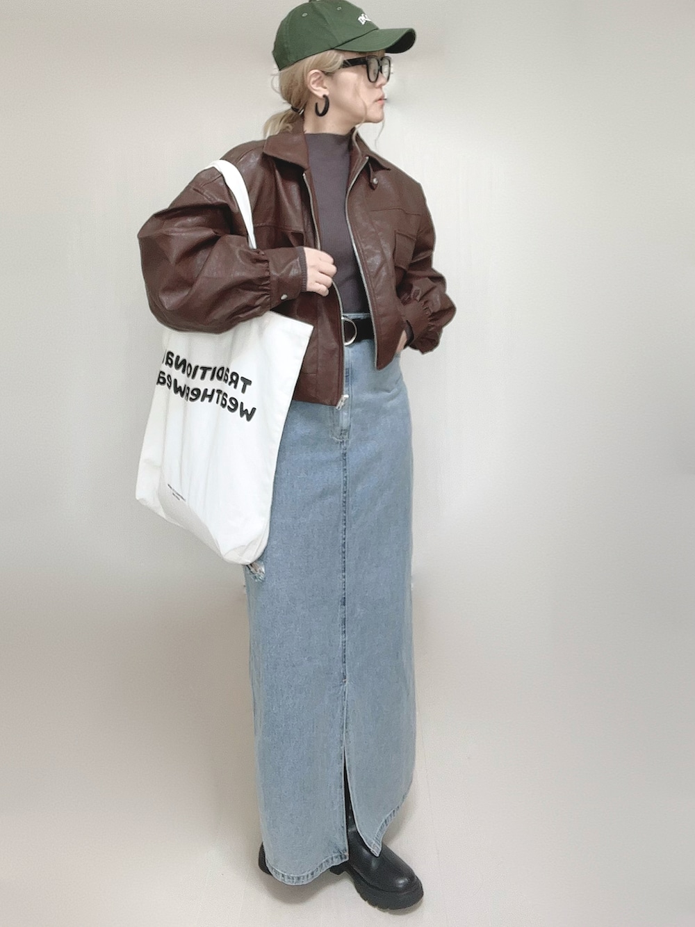 ブラウン系のブルゾン、ホワイト系のトートバッグ、ブラック系のブーツを着用したレディースの秋コーディネートの2枚目の写真