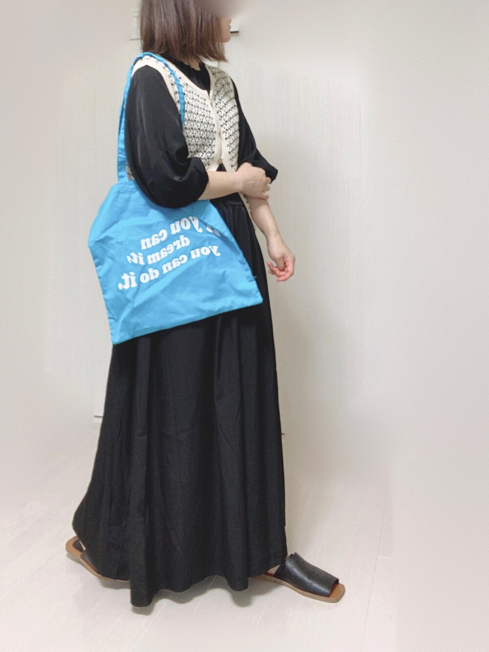 ブラック系のワンピース、ブルー系のトートバッグ、ブラック系のサンダルを着用したレディースの夏コーディネートの3枚目の写真