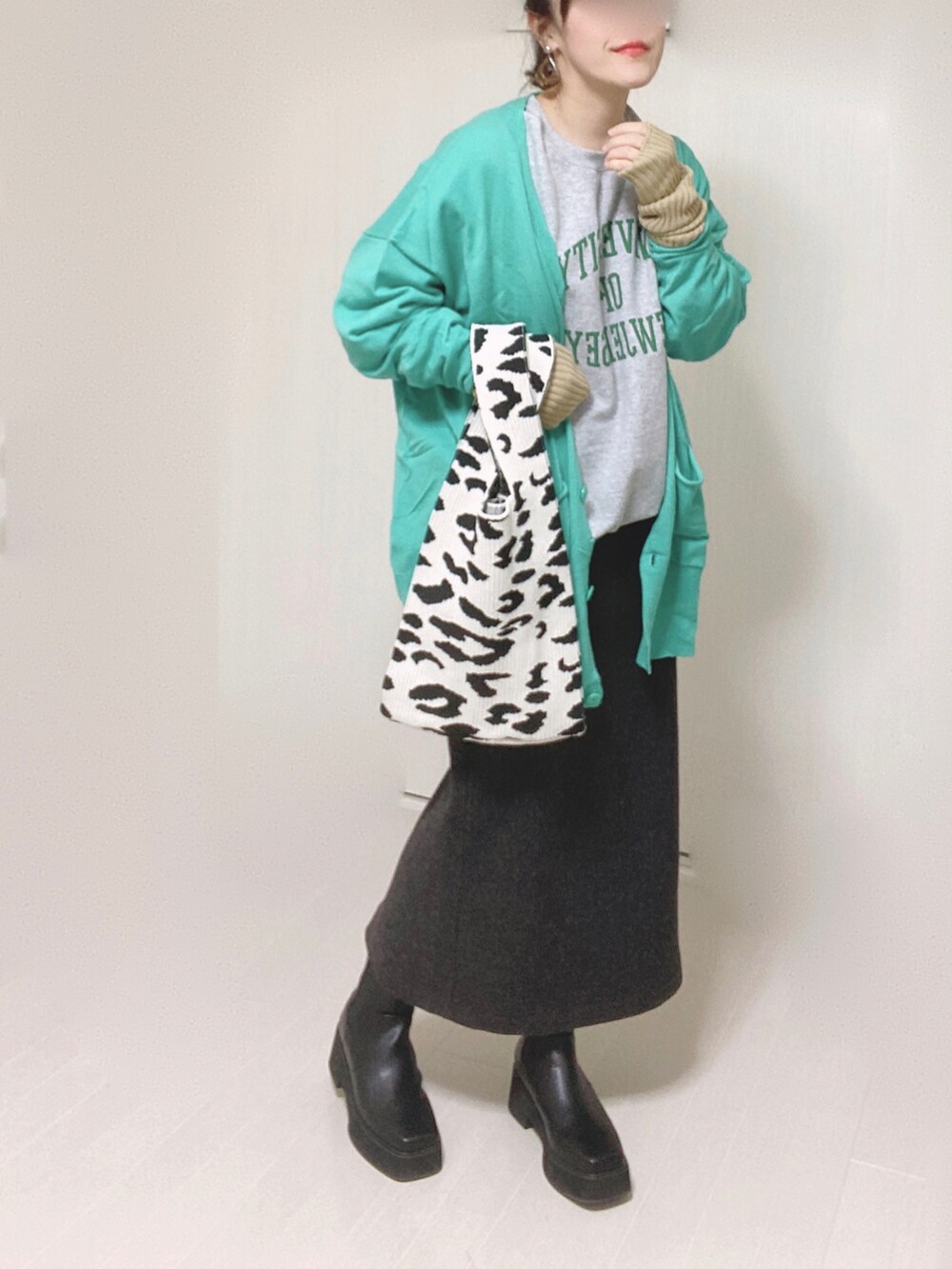 グレー系のスウェット、グリーン系のカーディガン/ボレロ、ブラック系のブーツを着用したレディースの冬コーディネートの2枚目の写真