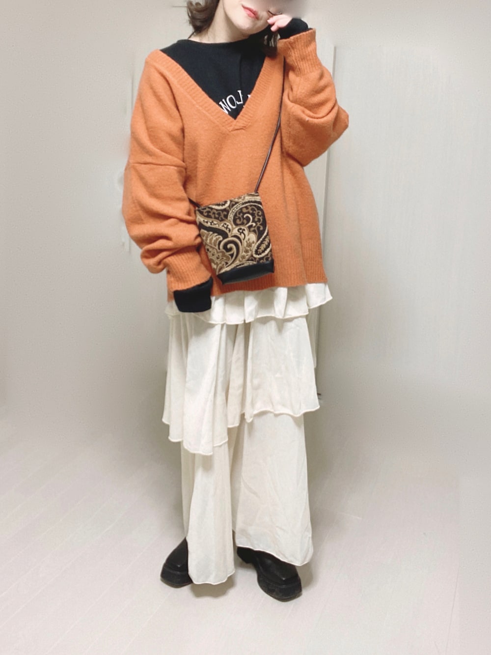 オレンジ系のニット/セーター、ブラック系のスウェット、ブラック系のショルダーバッグを着用したレディースの冬コーディネートの2枚目の写真