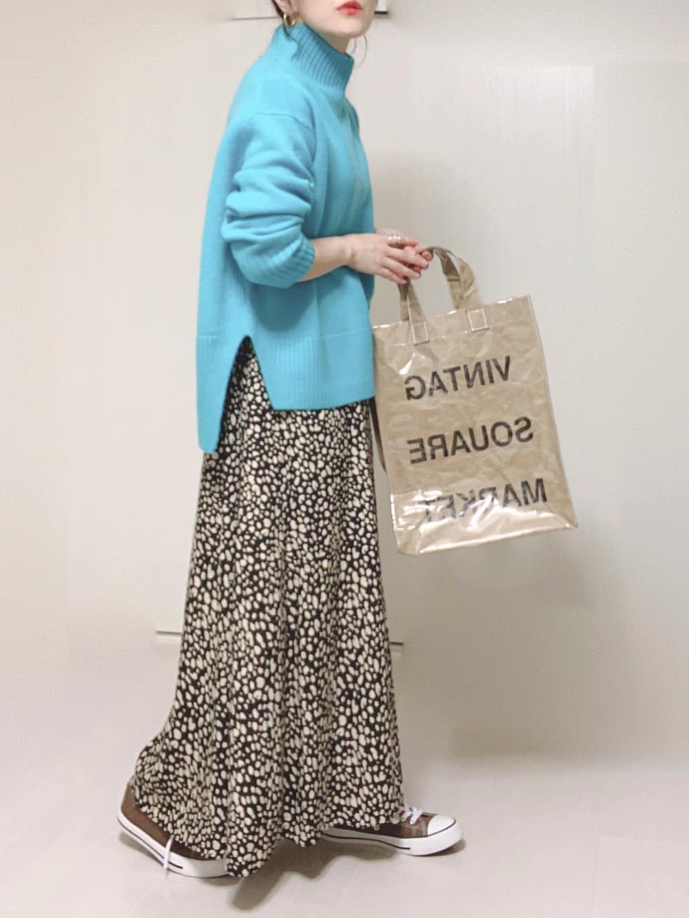 ブルー系のニット/セーター、グリーン系のトートバッグ、ブラック系のスカートを着用したレディースの秋コーディネートの4枚目の写真