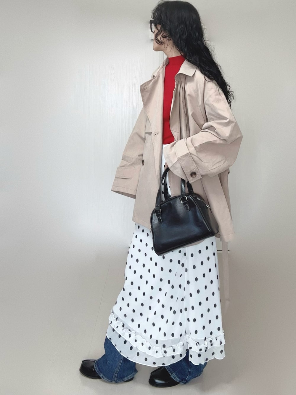 レッド系のニット/セーター、ベージュ系のトレンチコート、ブラック系のボストンバッグを着用したレディースの春コーディネートの2枚目の写真