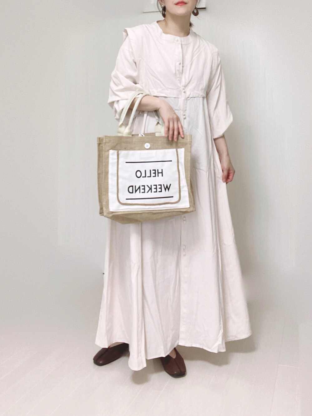 ホワイト系のシャツワンピース、ホワイト系のかごバッグ、ブラウン系のパンプスを着用したレディースの秋コーディネートの3枚目の写真