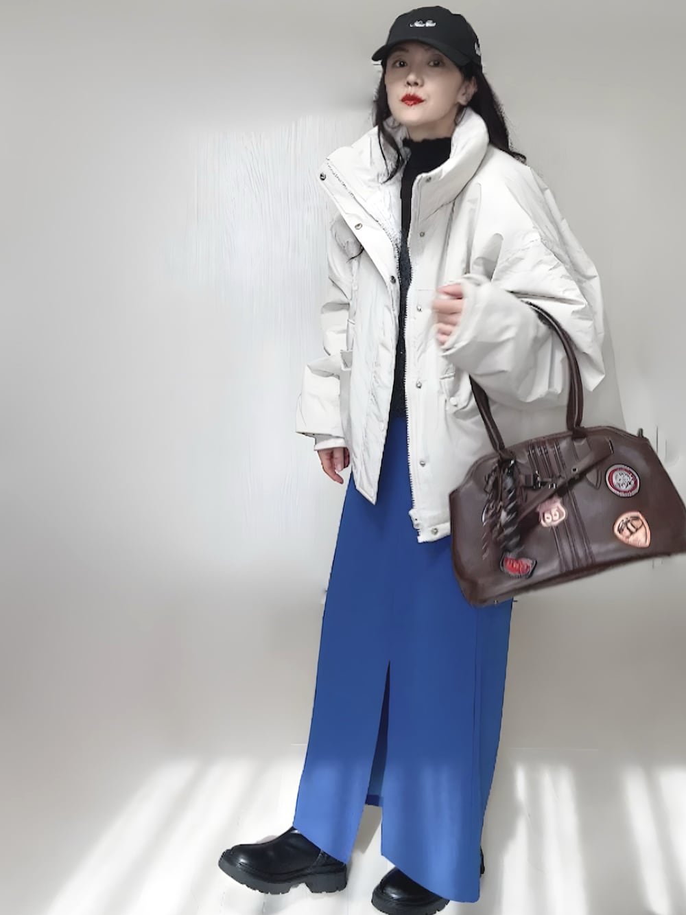 ホワイト系のブルゾン、ブラック系のブーツ、グレー系のベストを着用したレディースの秋コーディネートの5枚目の写真