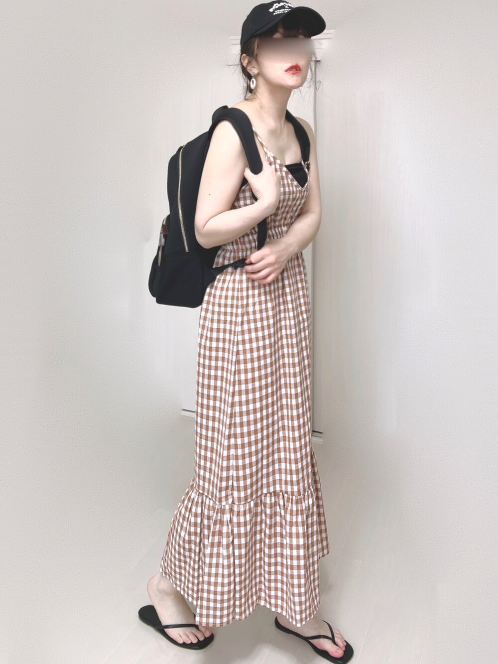 ブラック系のバックパック/リュック、オレンジ系のワンピース、ブラック系のサンダルを着用したレディースの夏コーディネートの3枚目の写真