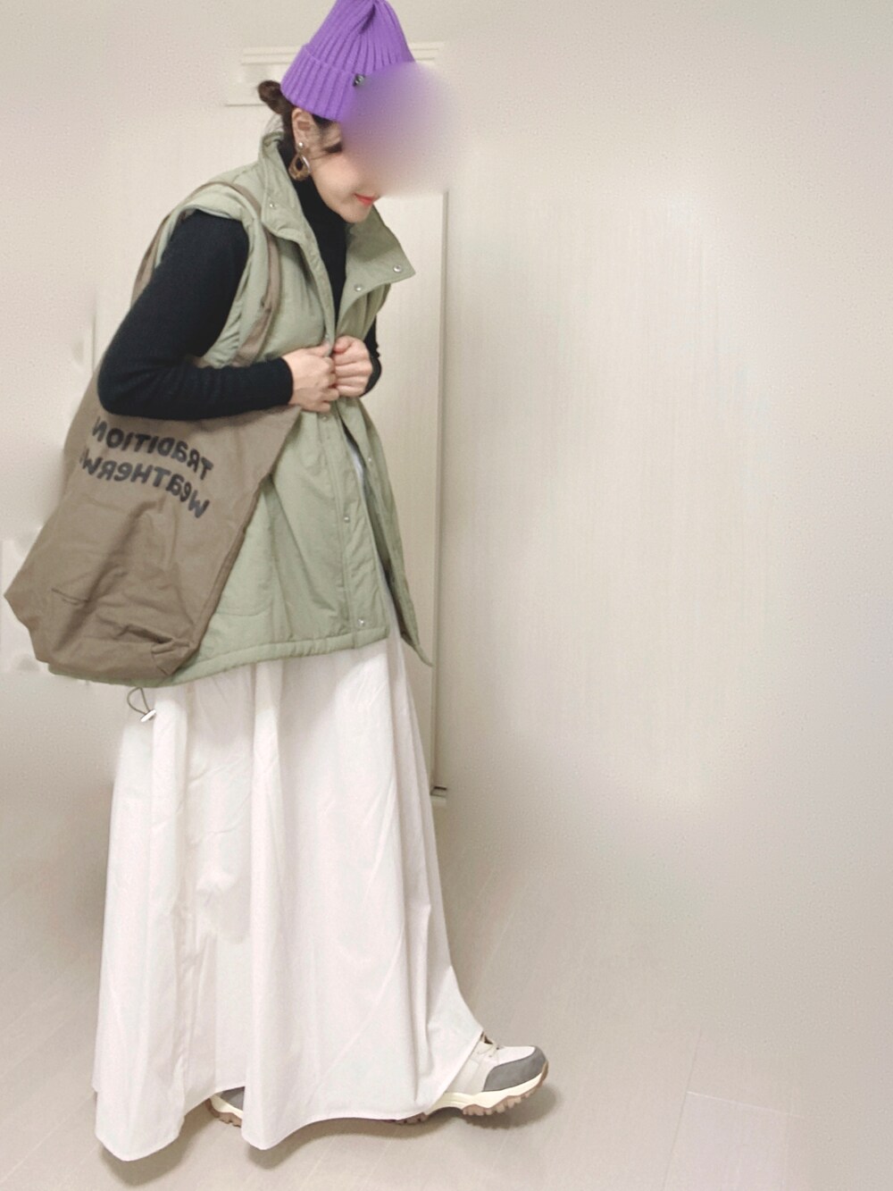 グリーン系のダウンジャケット/コート、ホワイト系のスカート、ベージュ系のスニーカーを着用したレディースの秋コーディネートの2枚目の写真