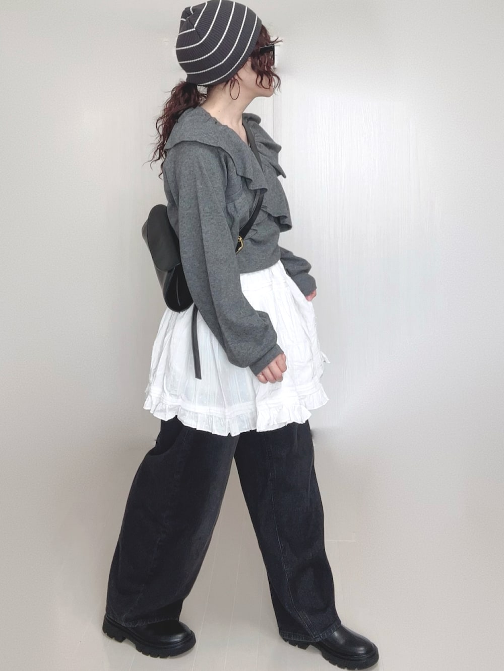 グレー系のニット/セーター、ブラック系のデニムパンツ、ホワイト系のスカートを着用したレディースの秋コーディネートの4枚目の写真