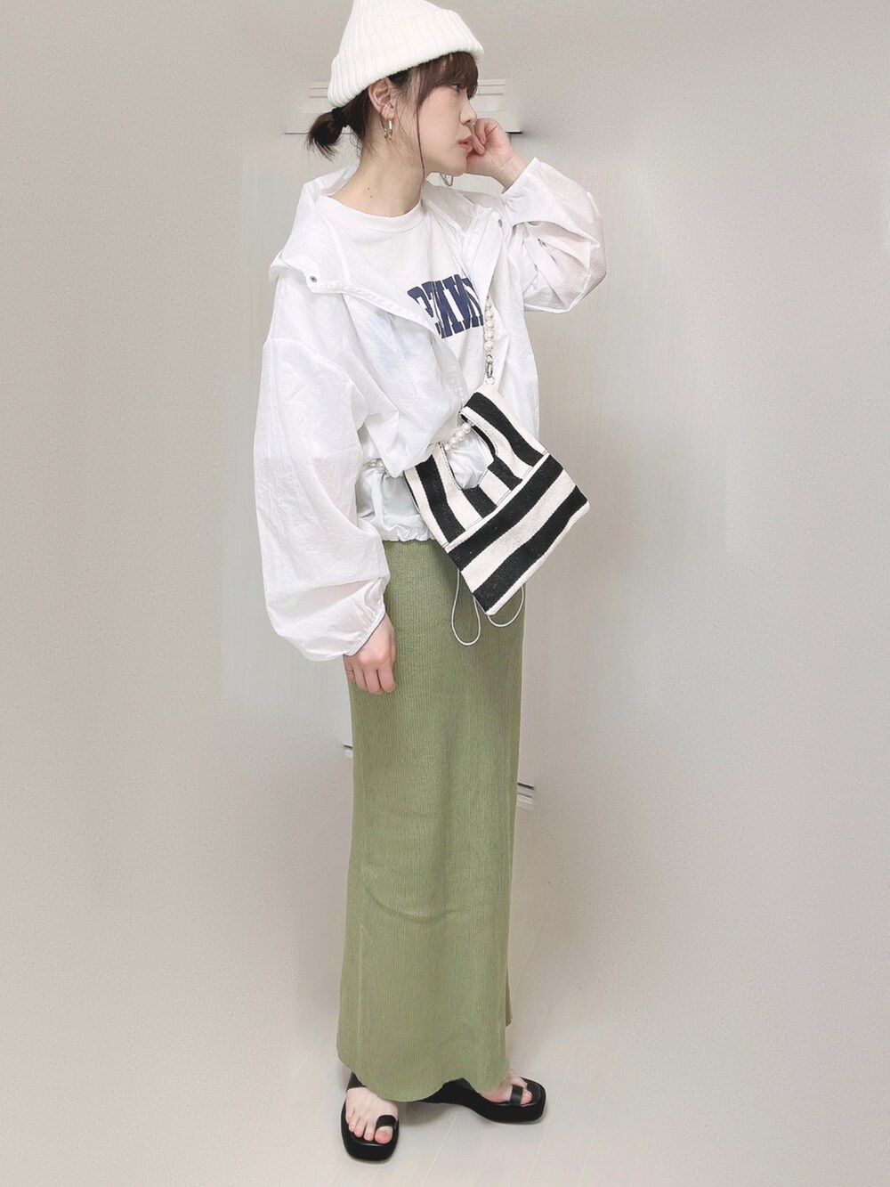 グリーン系のスカート、ホワイト系のショルダーバッグ、ブラック系のサンダルを着用したレディースの春コーディネートの3枚目の写真