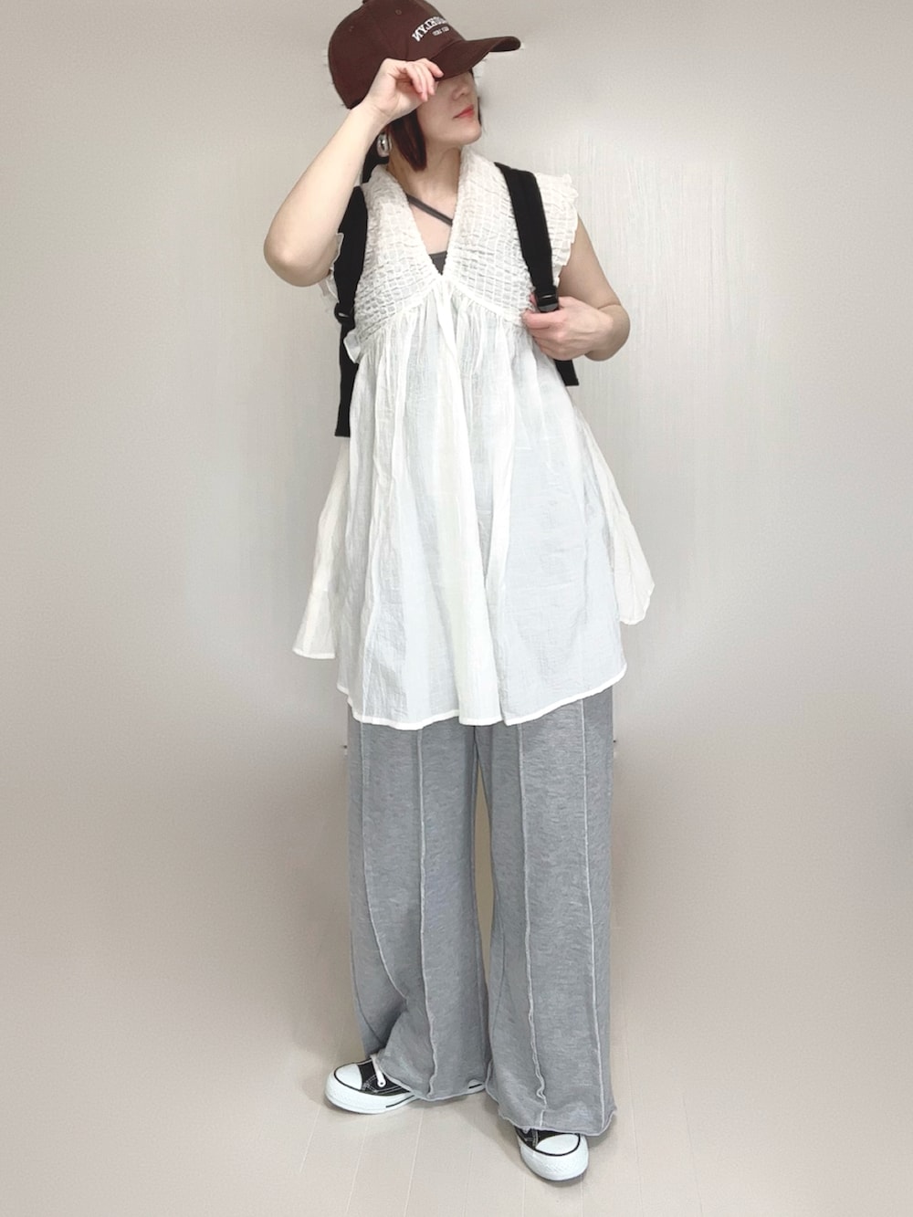 ホワイト系のワンピース、ブラック系のバックパック/リュック、グレー系のスウェットパンツを着用したレディースの春コーディネートの2枚目の写真