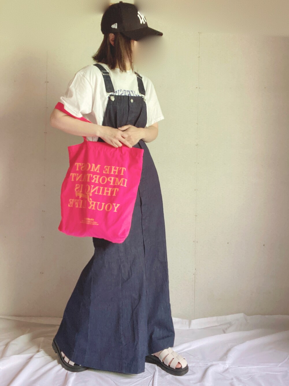 ブルー系のジャンパースカート、ホワイト系のTシャツ/カットソー、ピンク系のトートバッグを着用したレディースの夏コーディネートの2枚目の写真