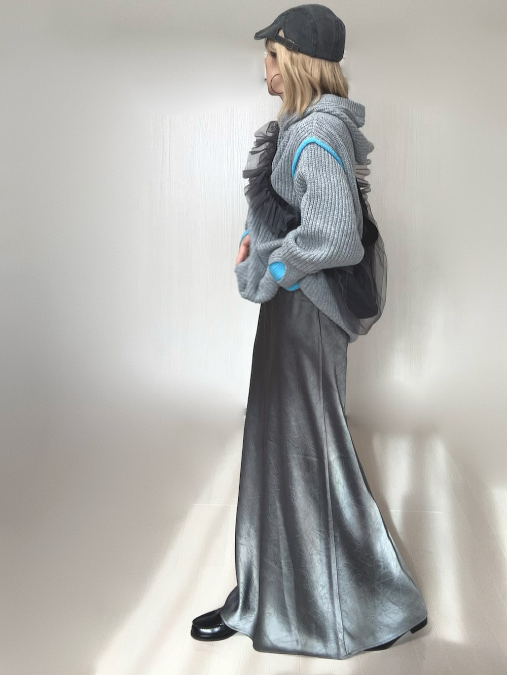 グレー系のニット/セーター、グレー系のスカート、グレー系のショルダーバッグを着用したレディースの冬コーディネートの2枚目の写真