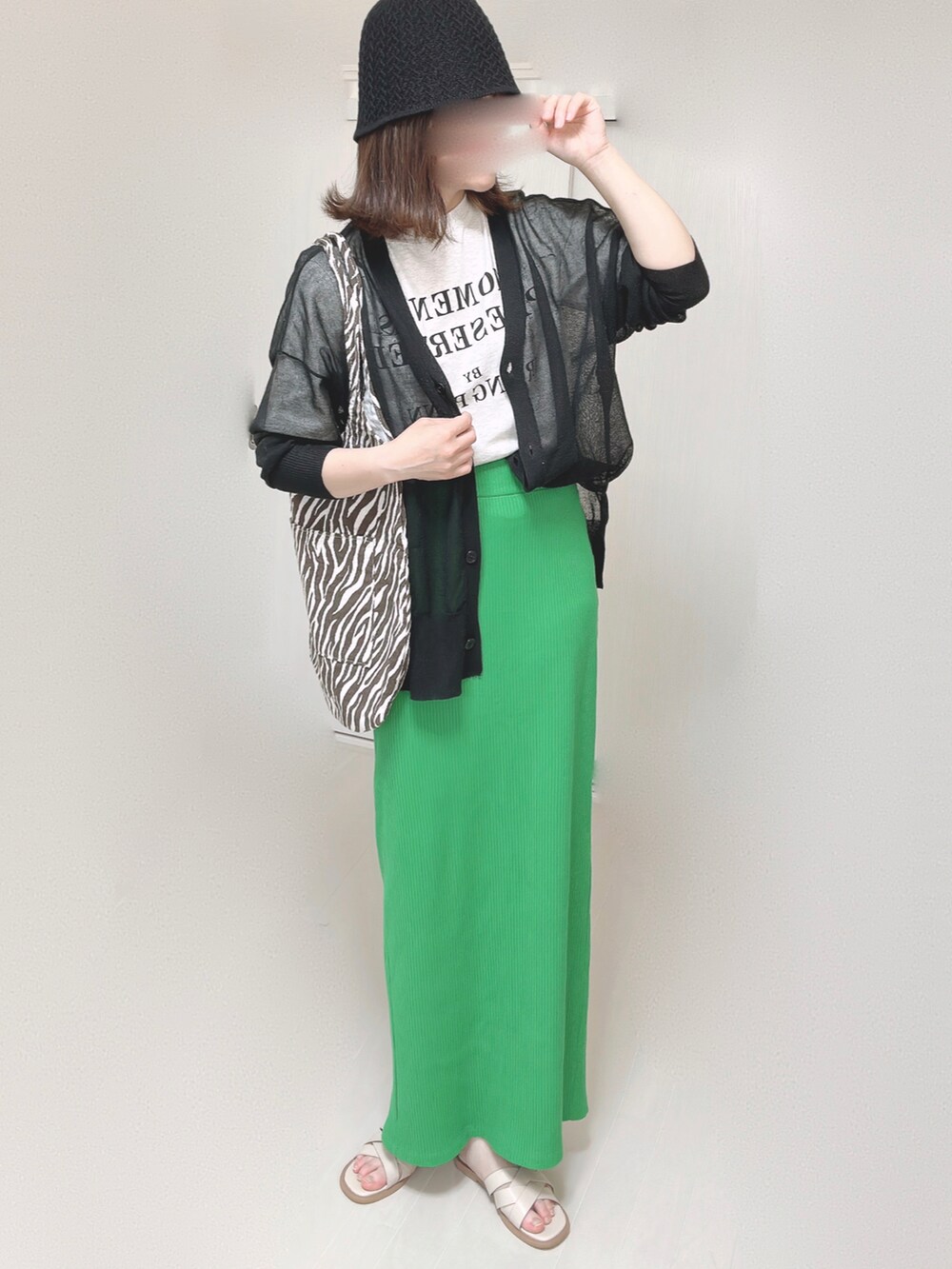 ブラック系のカーディガン/ボレロ、グリーン系のスカート、ホワイト系のサンダルを着用したレディースの夏コーディネートの2枚目の写真