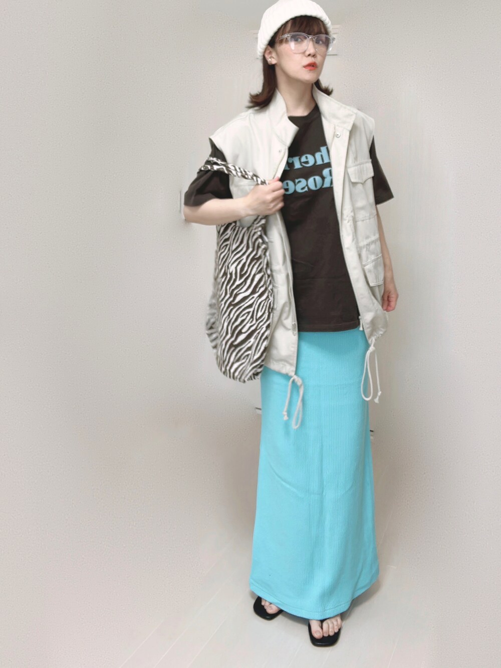 グレー系のTシャツ/カットソー、ホワイト系のベスト、ブルー系のスカートを着用したレディースの夏コーディネートの5枚目の写真