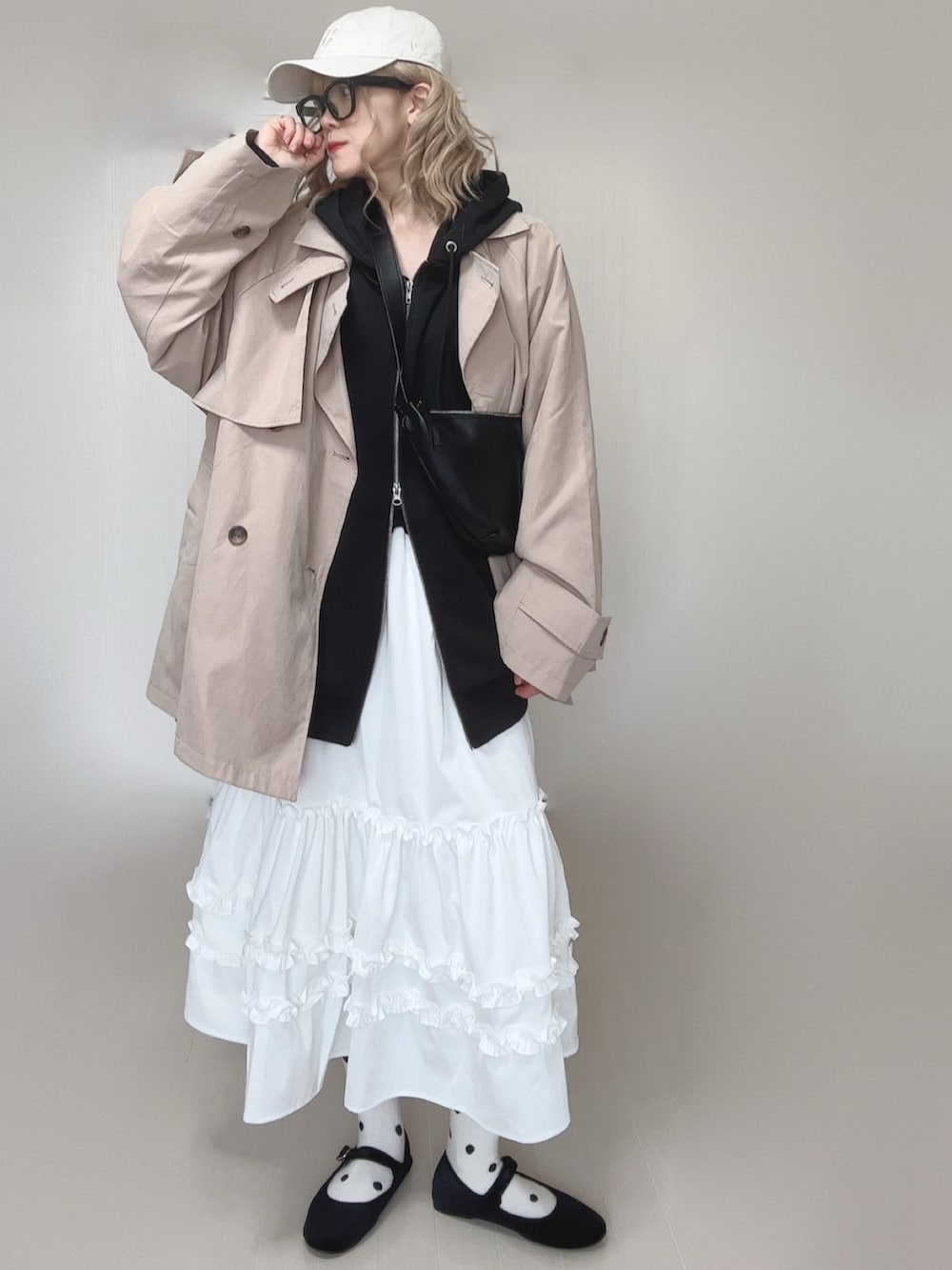 ブラック系のパーカー、ホワイト系のスカート、ベージュ系のトレンチコートを着用したレディースの春コーディネートの5枚目の写真