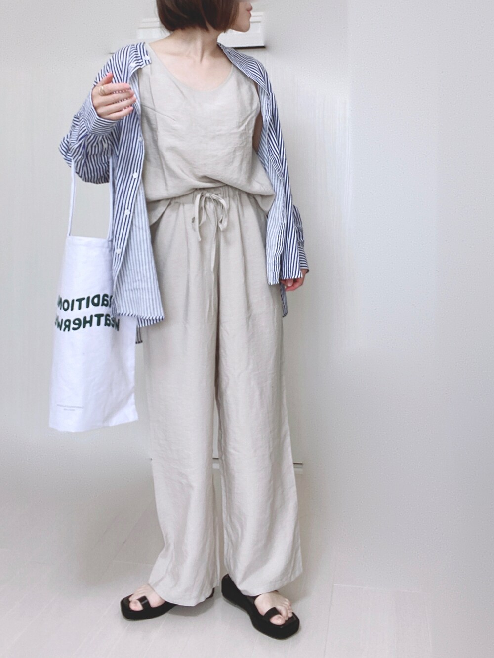 ブルー系のシャツ/ブラウス、ホワイト系のトートバッグ、ブラック系のサンダルを着用したレディースの夏コーディネートの4枚目の写真