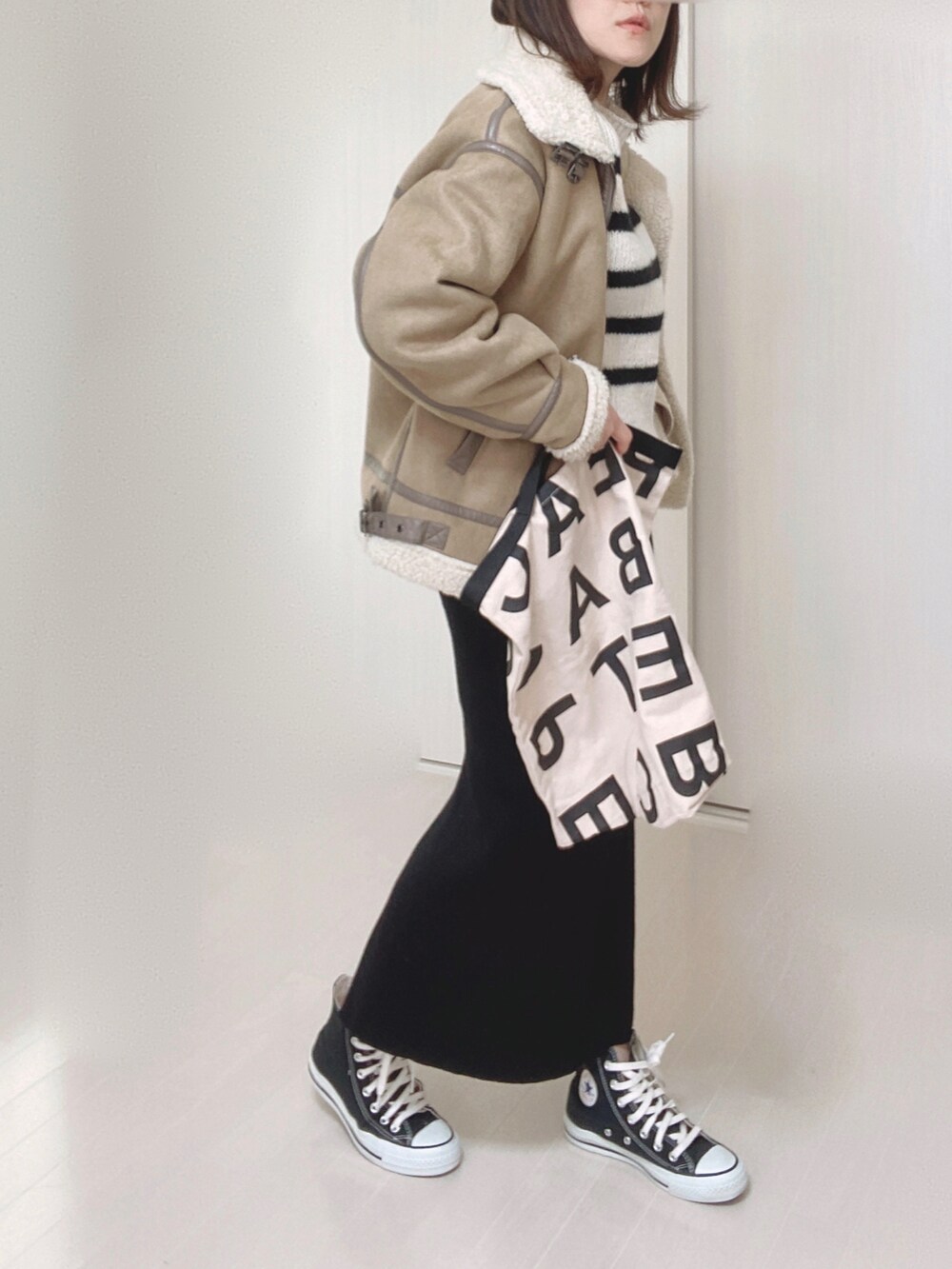 ホワイト系のニット/セーター、ベージュ系のムートンコート、ホワイト系のトートバッグを着用したレディースの冬コーディネートの4枚目の写真