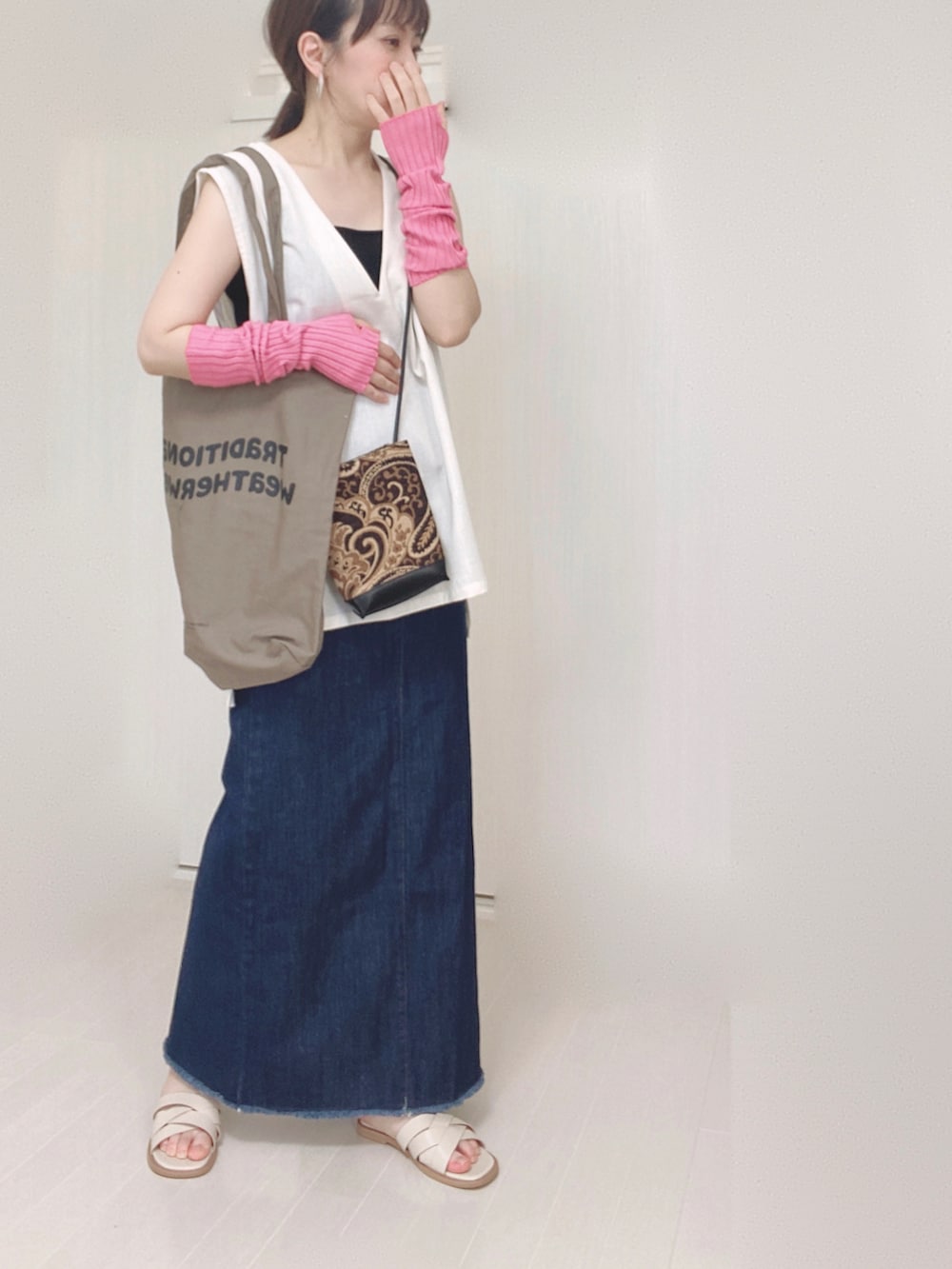 ブルー系のデニムスカート、ブラウン系のトートバッグ、ブラック系のショルダーバッグを着用したレディースの夏コーディネートの4枚目の写真