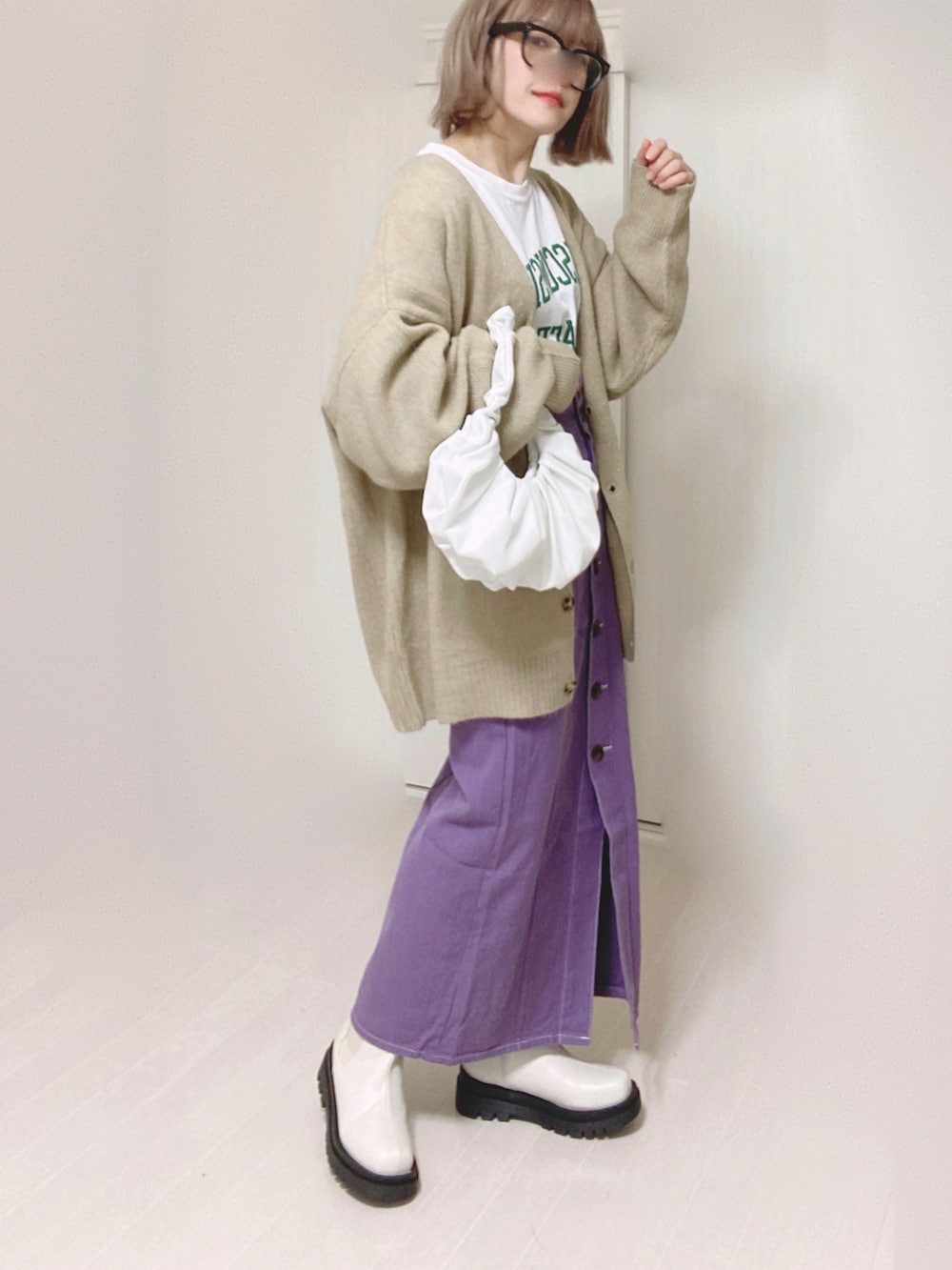 ベージュ系のカーディガン/ボレロ、ホワイト系のTシャツ/カットソー、パープル系のスカートを着用したレディースの冬コーディネートの2枚目の写真