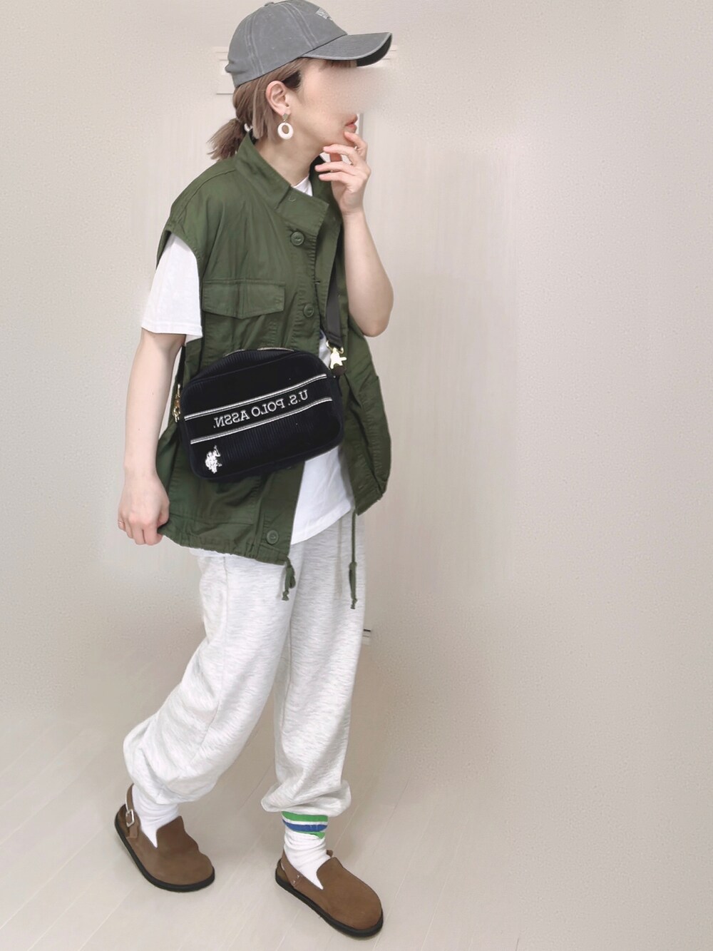 ブラック系のショルダーバッグ、ホワイト系のTシャツ/カットソー、ブラウン系のスリッポンを着用したレディースの春コーディネートの2枚目の写真