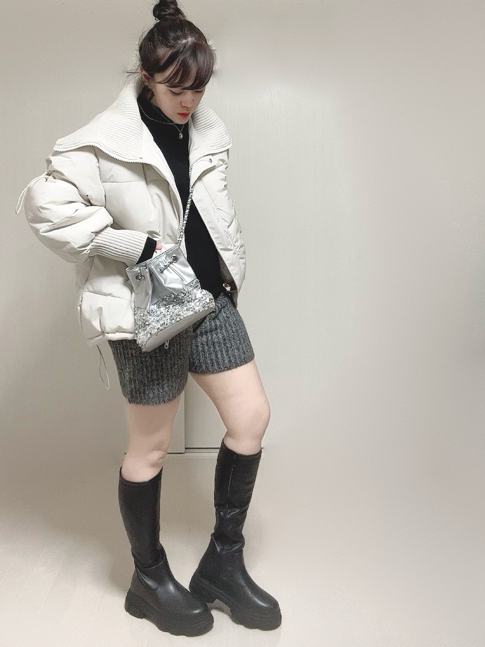 ホワイト系のダウンジャケット/コート、ブラック系のニット/セーター、ブラック系のブーツを着用したレディースの冬コーディネートの5枚目の写真