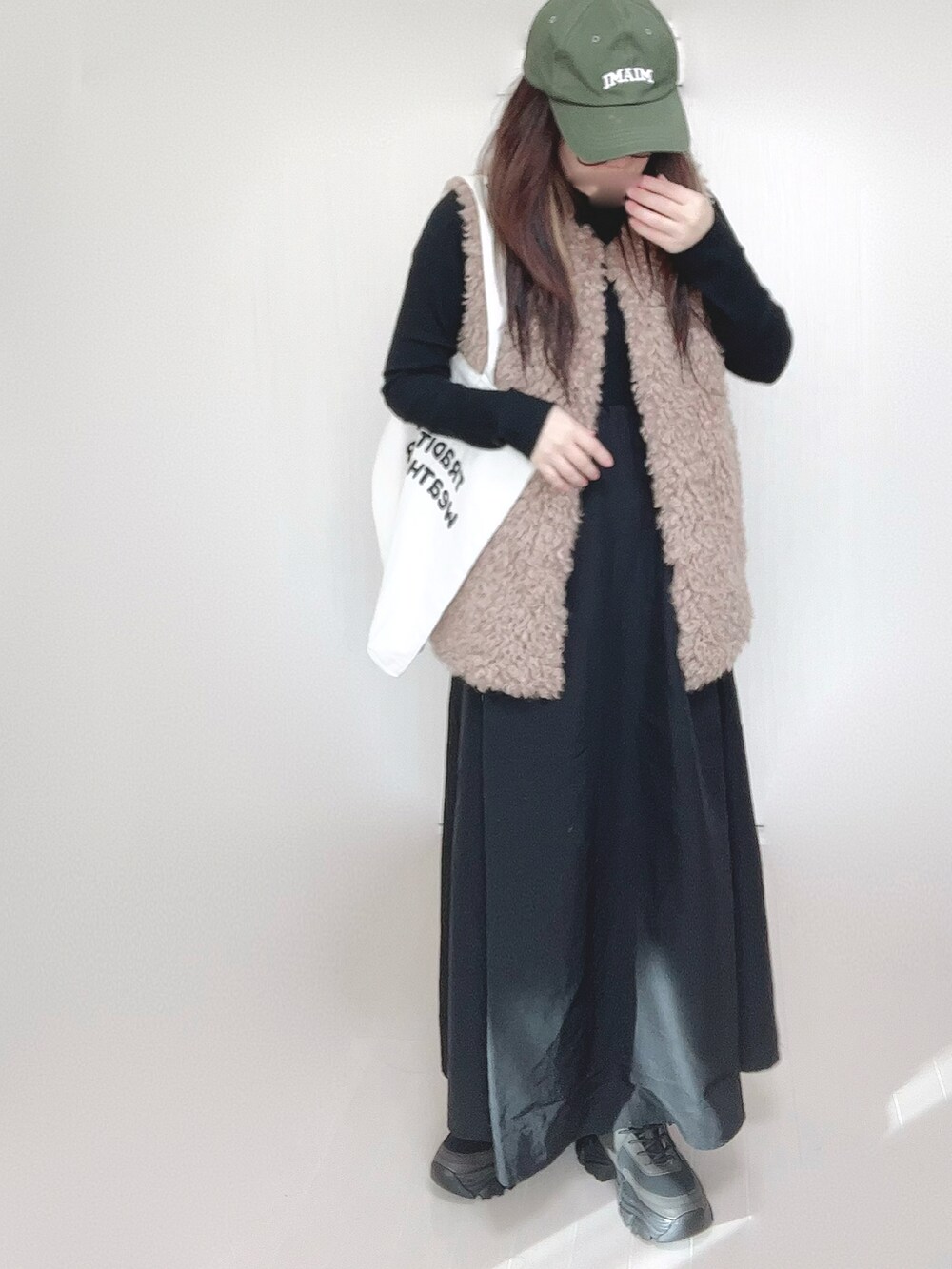グレー系のワンピース、ベージュ系のベスト、ホワイト系のトートバッグを着用したレディースの冬コーディネートの3枚目の写真