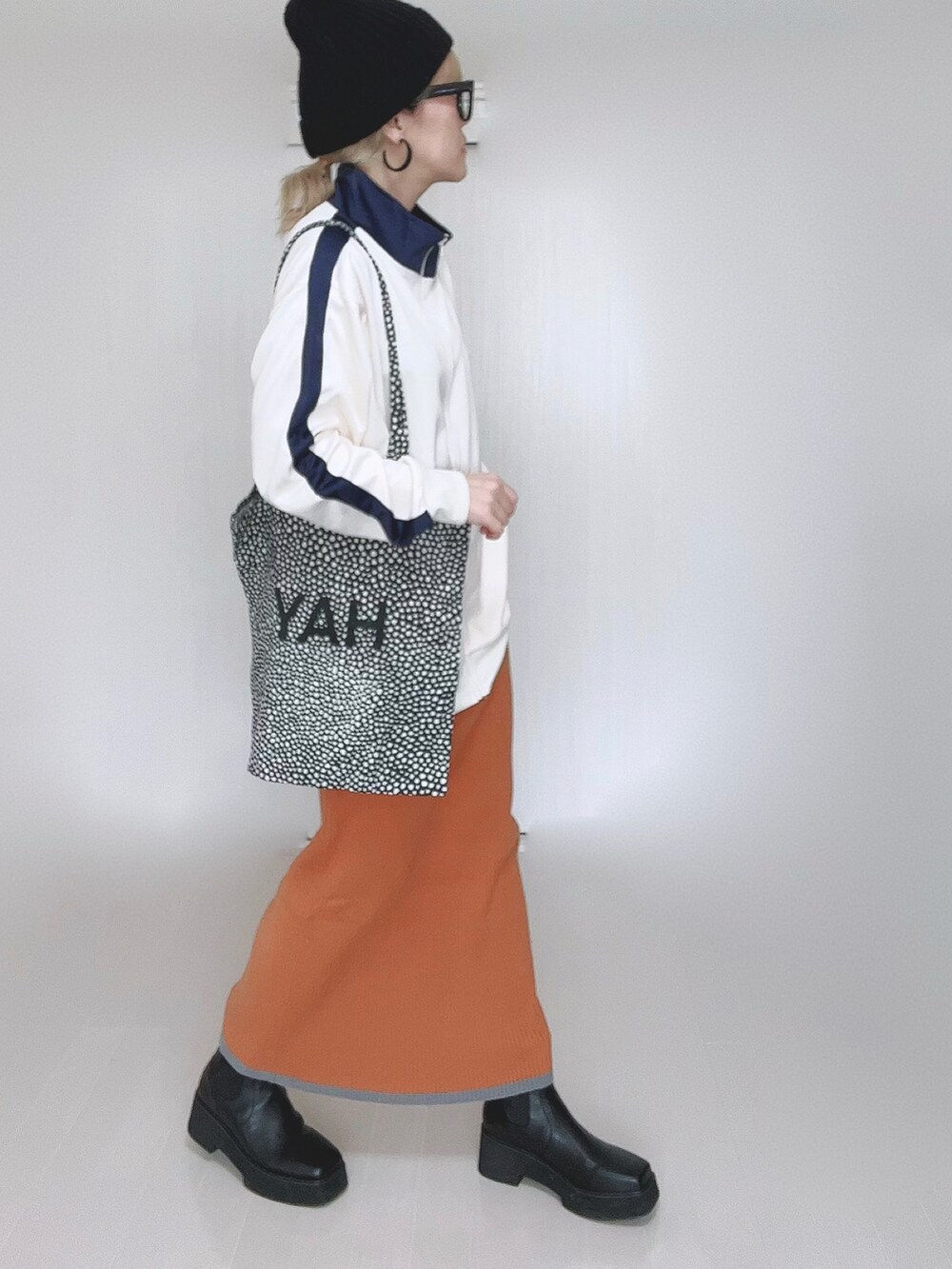 ベージュ系のジャージ、オレンジ系のスカート、ブラック系のブーツを着用したレディースの冬コーディネートの5枚目の写真