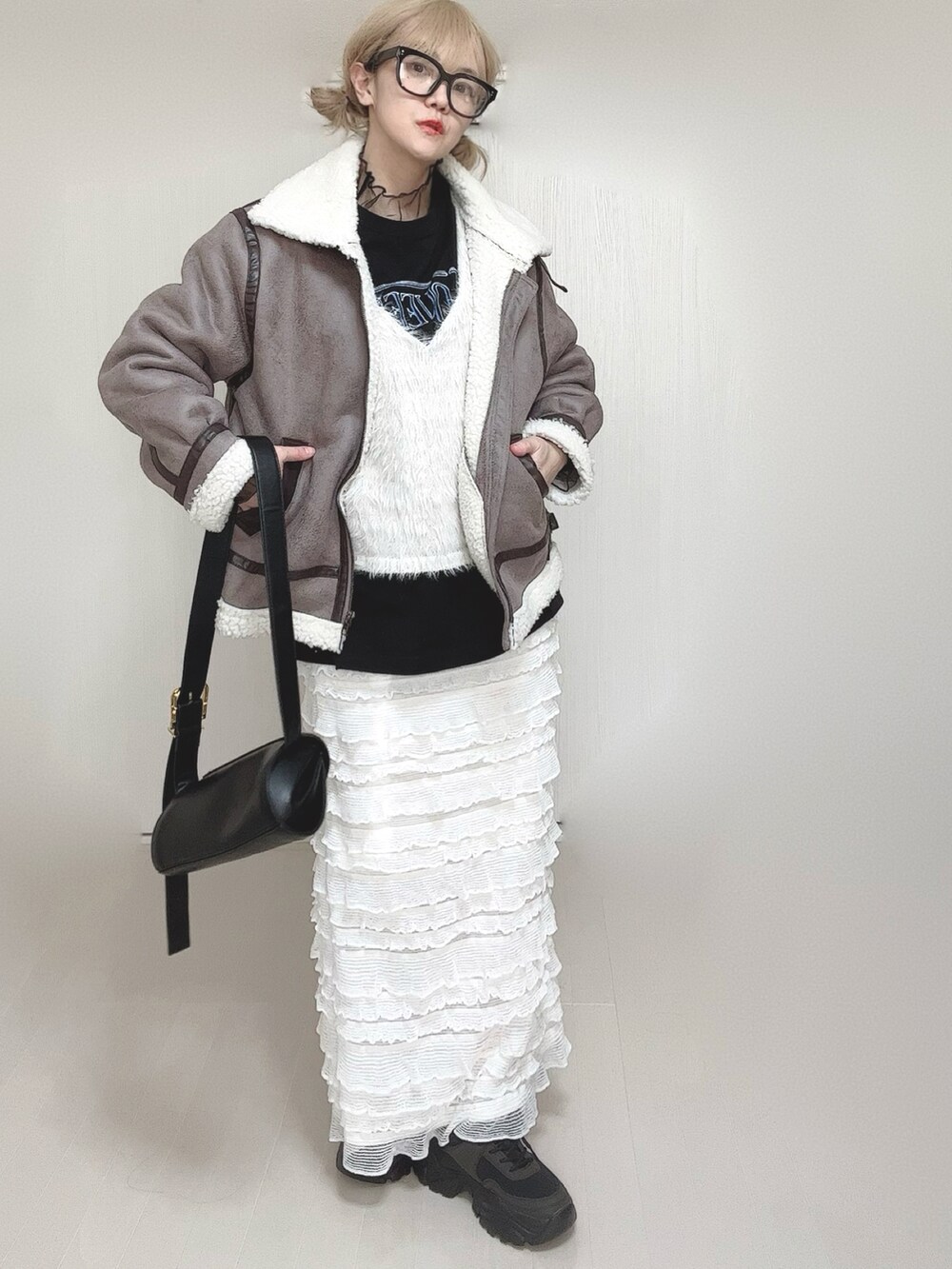 グレー系のムートンコート、ホワイト系のベスト、ブラック系のTシャツ/カットソーを着用したレディースの冬コーディネートの5枚目の写真