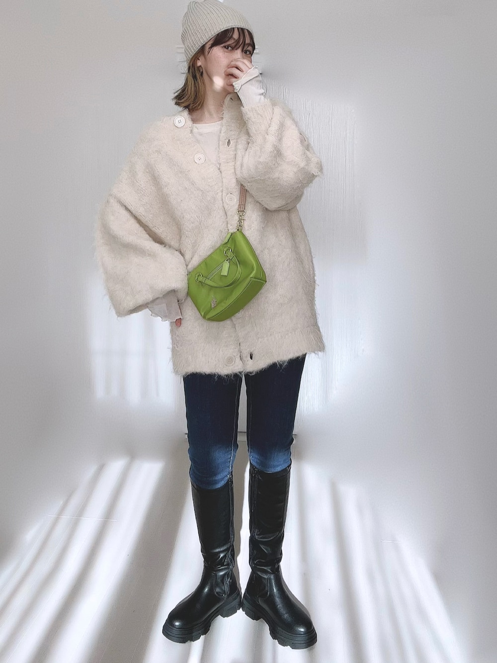 ブラック系のブーツ、ホワイト系のTシャツ/カットソー、ベージュ系のカーディガン/ボレロを着用したレディースの冬コーディネートの3枚目の写真