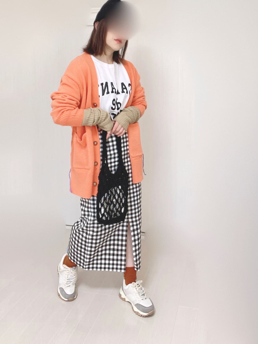 オレンジ系のカーディガン/ボレロ、ベージュ系のスニーカー、ホワイト系のTシャツ/カットソーを着用したレディースの秋コーディネートの4枚目の写真