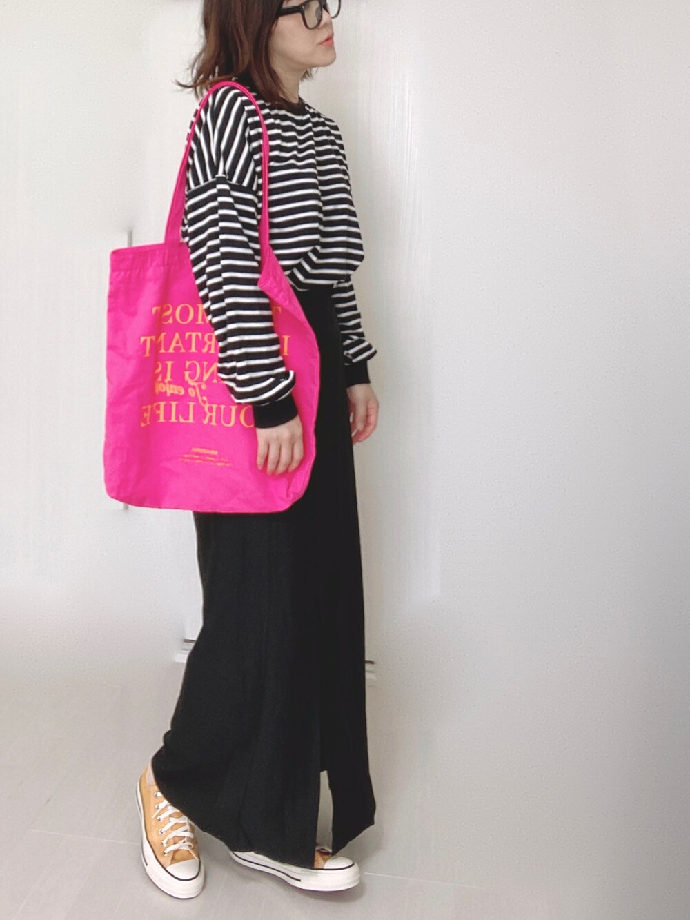 ブラック系のスカート、ホワイト系のTシャツ/カットソー、ピンク系のトートバッグを着用したレディースの秋コーディネートの2枚目の写真