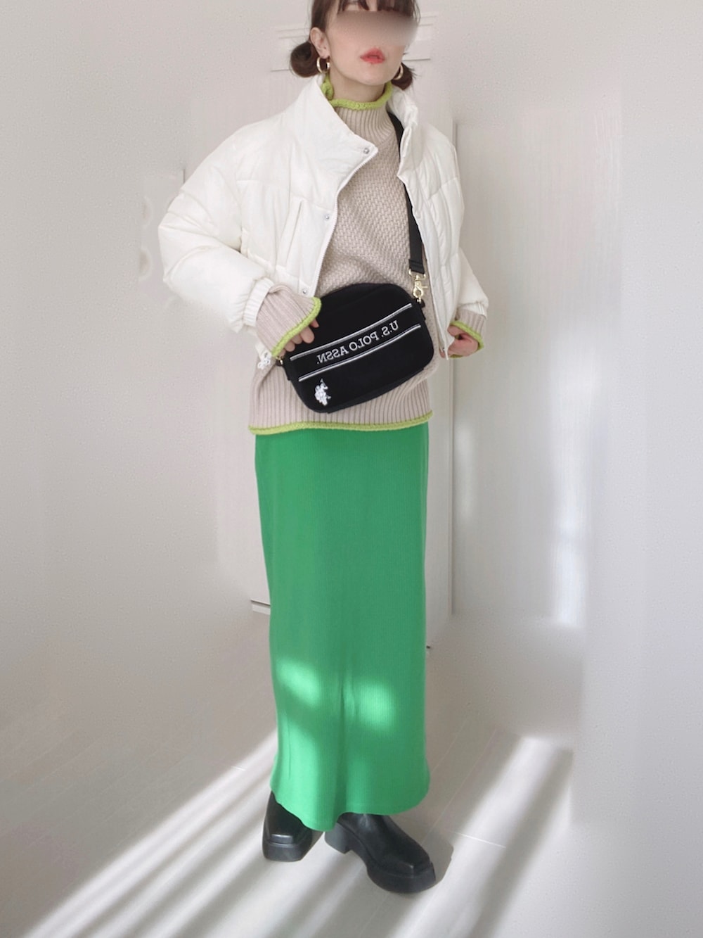 ブラック系のショルダーバッグ、ホワイト系のダウンジャケット/コート、ベージュ系のニット/セーターを着用したレディースの冬コーディネートの3枚目の写真