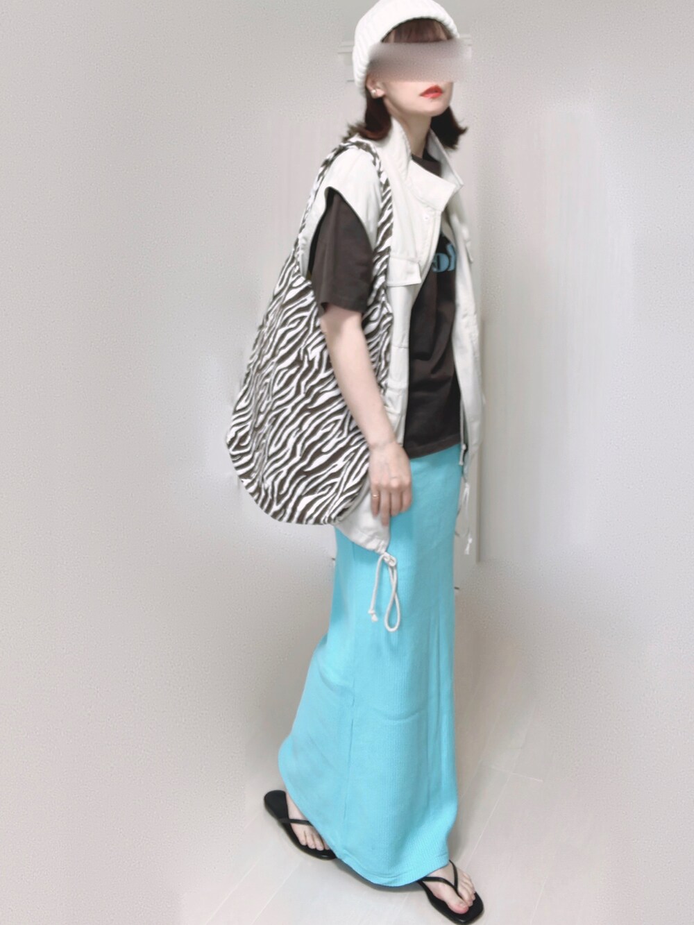 グレー系のTシャツ/カットソー、ホワイト系のベスト、ブルー系のスカートを着用したレディースの夏コーディネートの4枚目の写真