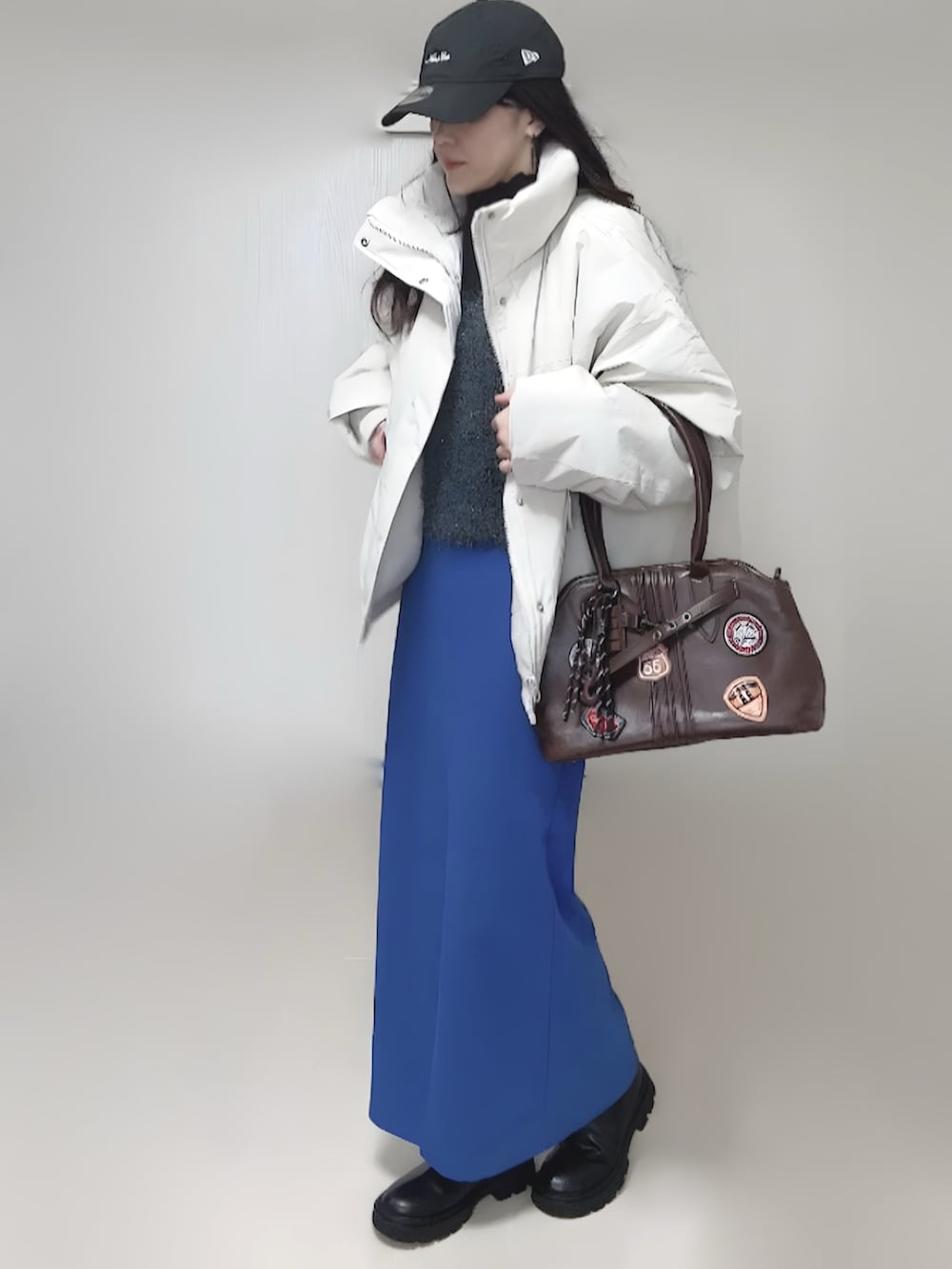 ホワイト系のブルゾン、ブラック系のブーツ、グレー系のベストを着用したレディースの秋コーディネートの2枚目の写真