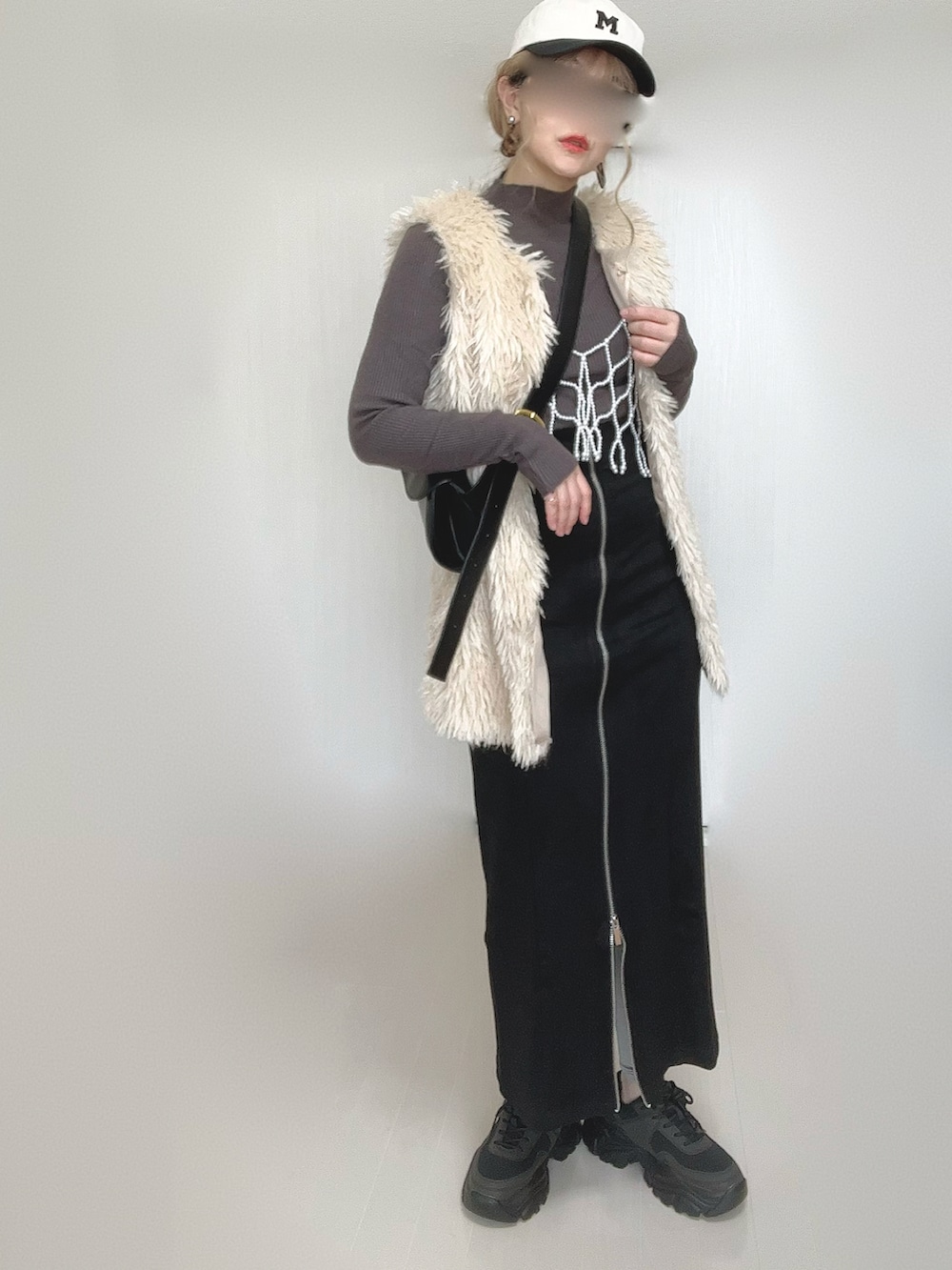 ブラック系のスカート、ホワイト系のベスト、ブラック系のスニーカーを着用したレディースの秋コーディネートの3枚目の写真